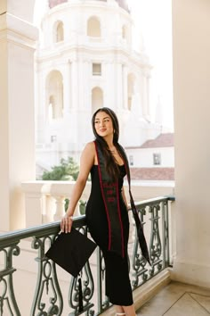 a woman is standing on a balcony near a building