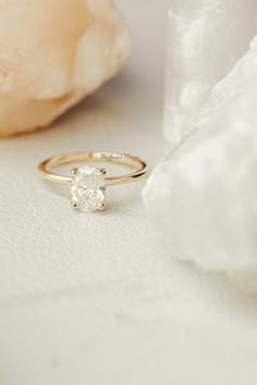 a diamond ring sitting on top of a white surface next to a flower and rock