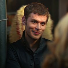 a man is smiling while standing in front of a mirror with his head turned to the side