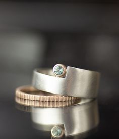 two wedding rings with one green diamond on top