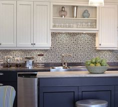 a bowl of fruit is sitting on the counter in this white and blue kitchen with stainless steel appliances