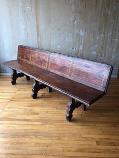 a wooden bench sitting on top of a hard wood floor next to a white wall