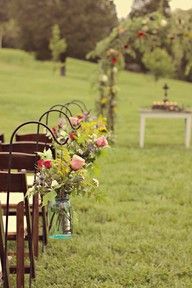 a row of wooden chairs sitting on top of a lush green field covered in flowers