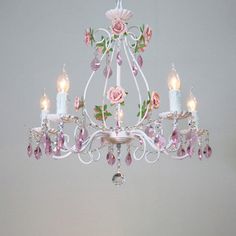 a white chandelier with pink flowers and candles