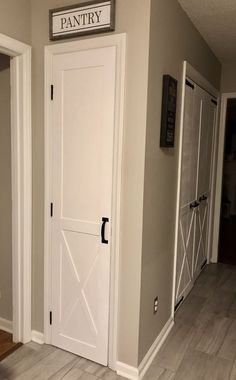 two white doors in a room with wood floors and gray walls, one has a pantry sign above the door