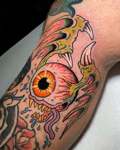 a man's arm with tattoos on it and an orange eye in the center