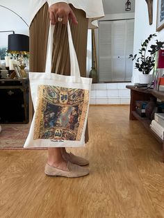 a person holding a bag with a painting on it in the middle of a room