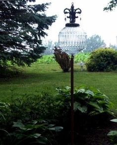 a bird feeder sitting on top of a wooden pole in the middle of a garden