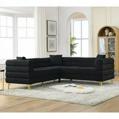 a black sectional sofa sitting on top of a white rug