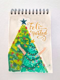 a spiral notebook with a drawing of a christmas tree on the cover and words feliz nabilad