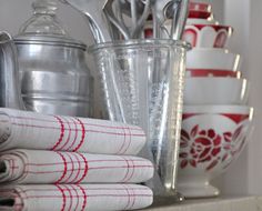 red and white kitchen towels stacked on top of each other in front of metal utensils