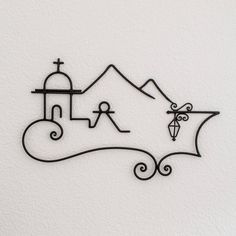 a metal wall hanging with a church and mountains in the background on a white wall