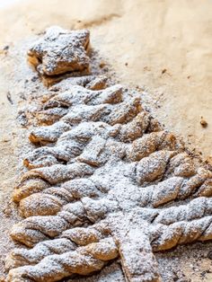 a pastry with powdered sugar on it is laying on the ground next to a piece of bread