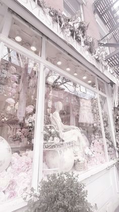 a store window with pink flowers in the front and white decorations on the windowsill