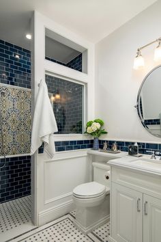 a white toilet sitting next to a bathroom sink under a large mirror on top of a wall