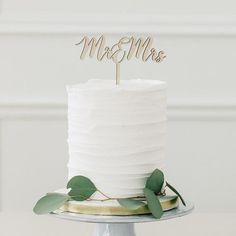 a white cake topped with a wooden mr and mrs topper