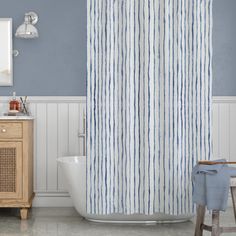 a blue and white striped shower curtain next to a bathtub in a bathroom with gray walls