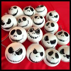 a pile of white pumpkins with faces painted on them sitting on a red surface