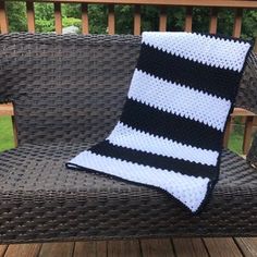 a black and white crocheted blanket sitting on top of a brown wicker couch