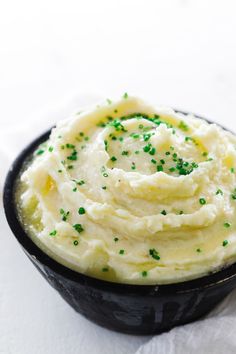 mashed potatoes with green sprinkles in a black bowl