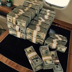 stacks of money sitting on top of a black rug in front of a window next to a toilet