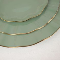 three green plates with gold trim on them