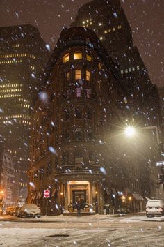 snow falling on the ground in front of a building