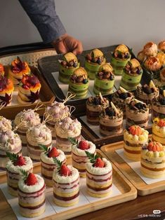 a table topped with lots of different types of cakes and desserts on top of wooden trays