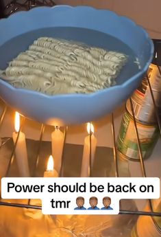 a blue bowl filled with noodles sitting on top of a stove next to some candles