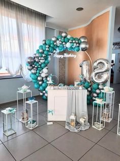 a balloon arch is decorated with silver, teal and white balloons in the shape of numbers