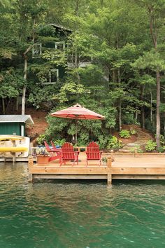 a dock with chairs and an umbrella next to a house on stilts in the water