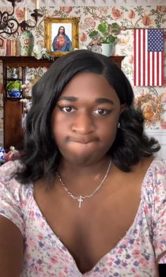 a woman is looking at the camera with an american flag on the wall behind her