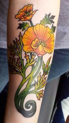 a person with a tattoo on their arm that has yellow flowers and green leaves growing out of it