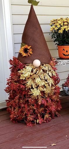 a scarecrow made out of fake leaves and pumpkins sitting on the front porch