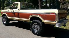 a tan and brown truck parked on the side of a road in front of trees