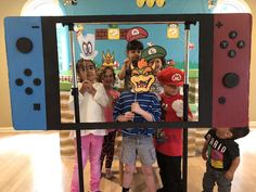 children standing in front of a video game screen with mario and luigi masks on it