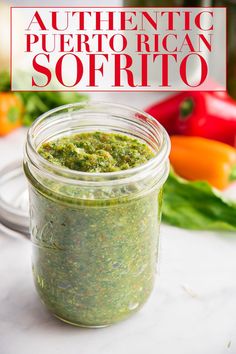 a jar filled with green pest sitting on top of a counter next to some vegetables