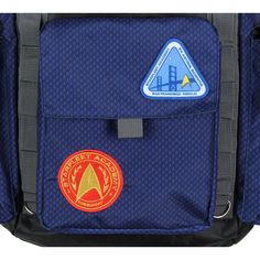 This Star Trek backpack is for all your space travels! It features an embroidered Starfleet Academy insignia. The backpack features several patches with the same Starfleet Academy logo as pictured throughout the years on the show. On one of the sides, it features "Est. 2161." The backpack features many cargo-style pockets, including dual side pockets and a smaller one on the front for fitting all your Star Trek merchandise! It also features an inner laptop sleeve in the main backpack and a roll- Blue Travel Bag With Logo Patch, Zelda Backpack, Star Wars Loungefly Backpack, Disney Loungefly Backpack Star Wars, Starfleet Academy, Academy Logo, Star Trek Merchandise, Blue Travel Backpack With Anti-theft Pocket, Travel School