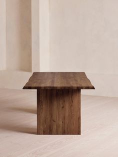 a wooden table sitting on top of a hard wood floor next to a white wall