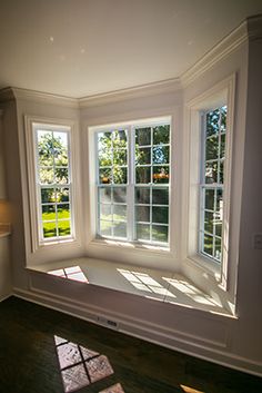 an empty kitchen with three windows and wood flooring on the other side of the room