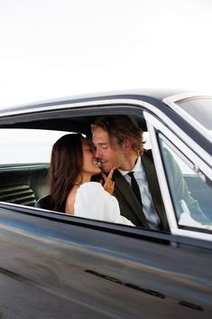 a man and woman are kissing in the back seat of a car as they ride down the street