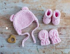 a knitted hat, booties and pacifier are laid out on a wooden surface