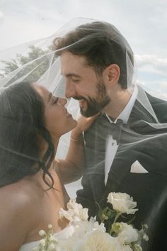 a bride and groom kissing under a veil