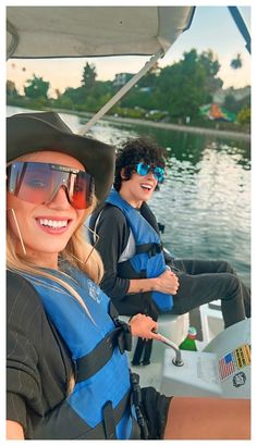 two people on a boat in the water wearing life jackets and sun glasses, smiling at the camera