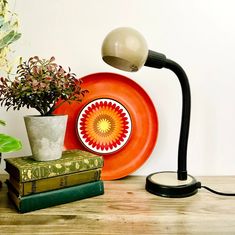 an orange plate sitting on top of a wooden table next to a lamp and books