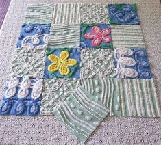 a close up of a patchwork quilt on a table cloth with flowers and leaves