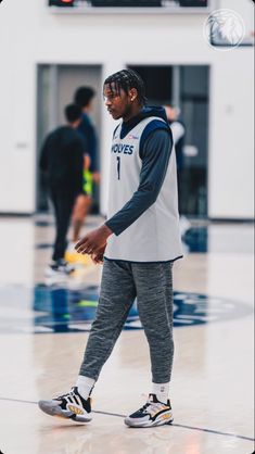 a man with dreadlocks walking on a basketball court