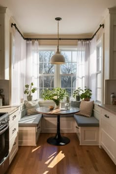 a kitchen with a table and some plants in the window sill next to it