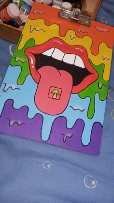 a painting of a woman's mouth and tongue on a blue sheet with other items nearby