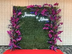 a red carpeted area with purple flowers and greenery on the wall behind it